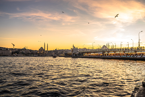 Istanbul, Turkey - February 6, 2024: Sunset hits Bosphorus Strait. Galata Bridge is packed with fishermen and tourists.