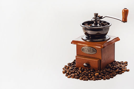 Hand coffee grinder and coffee beans on a white isolated background. Copy space.