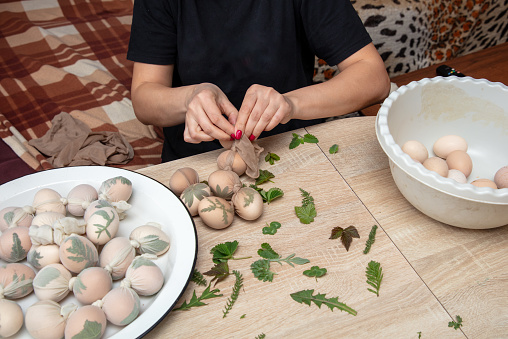 A girl cooks eggs in tights with leaves. Easter.