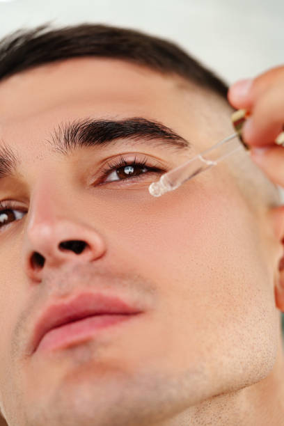 istock Handsome man applying skincare serum at camera close up 2032030746