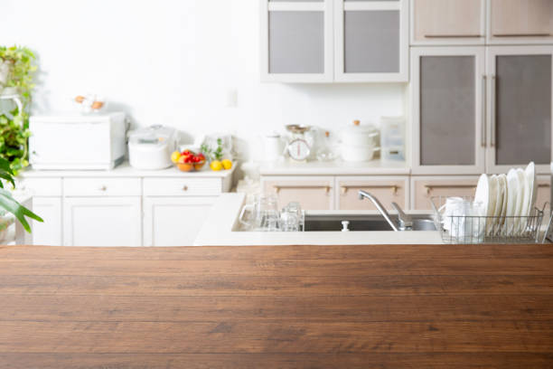 Stainless steel pot on a sleek induction hob beneath hanging metal utensils and light wood cabinetry, modern clean kitchen scene highlighting cookware, reflection and everyday cooking