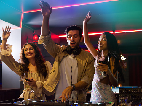 Dancing Womans  and DJ with headphones enjoying night party at night club .