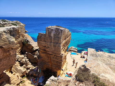 People sunbathing on the famous Cala del Bue Marino, a cliff with adjoining cave located on the island of Favignana in the Egadi Archipelago, Sicily, Italy.