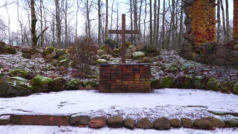 Walk by red bench and approach abandoned church cross, boulder wall remains