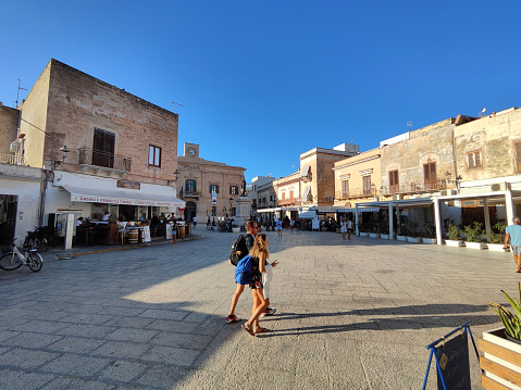 Tourists walking in Piazza Europa, a central square in Favignana, Egadi Archipelago, Sicily, Italy.