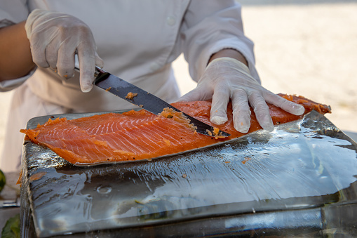 man chef cuts the salmon on the table for restaurant customer
