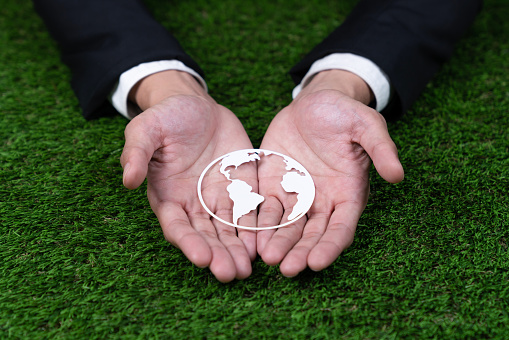 Businessman holding Earth planet icon symbolize eco-friendly business commitment to environmental protection and zero carbon emission. Earth World Day concept to promote eco awareness. Gyre