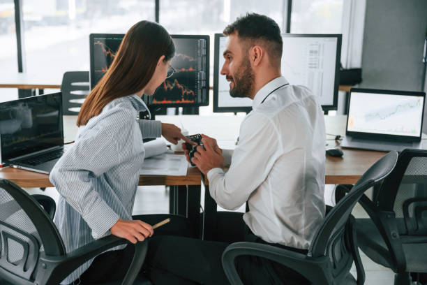 istock Graphs on a smartphone screen. Two employees are working in the office together 2032132099