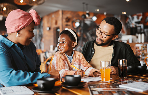 Black family, restaurant and eating with parents and child coloring with bonding, food and care. Love, diner and table with art and happy girl with notebook and hungry people in a cafe with drink