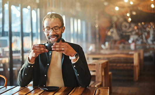 Happy black man, coffee and aroma at restaurant for morning, start or caffeine at dining table. African male person with smile for hot and steamy beverage, latte or cappuccino at cafeteria or shop