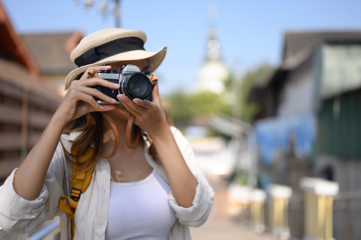 Female travel blogger taking photos with her camera of local city street in Chiang Mai, Thailand.