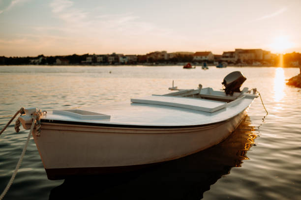 istock Small boat on calm water, moored in the harbor during sunset. 2032143820