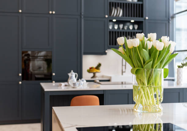 Fresh flowers on marble counter top in contemporary chic kitchen with dark cabinets