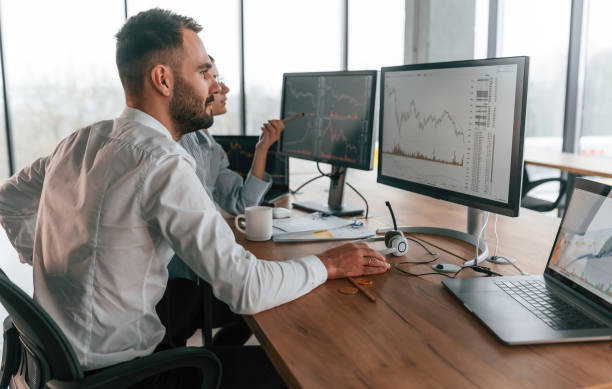 istock By the pc monitors. Two employees are working in the office together 2032158779