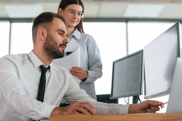 istock Silver colored laptop is on the table. Two employees are working in the office together 2032159291