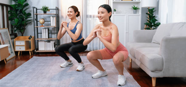 istock Vigorous energetic woman with trainer doing exercise at home with sport band. 2032174779