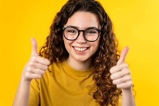 Happy young woman with glasses giving two thumbs up