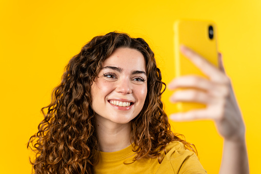 Happy woman in yellow taking a selfie, enjoying the moment