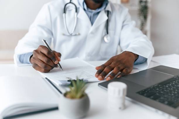 istock Writing information into the document. Black man as doctor in the clinic office 2032237096