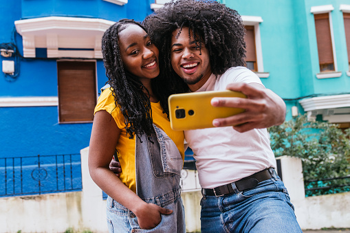 Latino friends enjoying a close-up selfie against a backdrop of urban vibrancy.