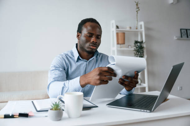 istock Reading information from document. Businessman is working in the office by laptop 2032248400