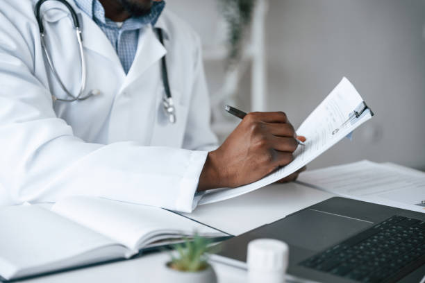 istock Writing information into the document. Black man as doctor in the clinic office 2032248925