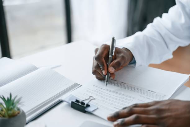istock Filling in the document, writing by using pen. Black man as doctor in the clinic office 2032248948