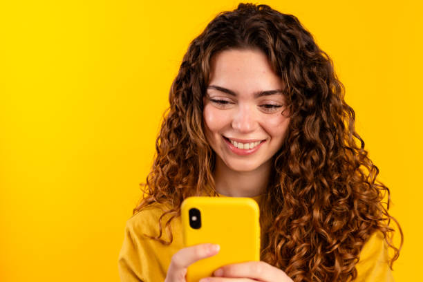 istock Smiling Woman Using Yellow Smartphone 2032258126