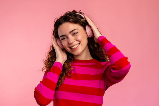 Joyful woman in a striped sweater enjoying tunes on her headphones.