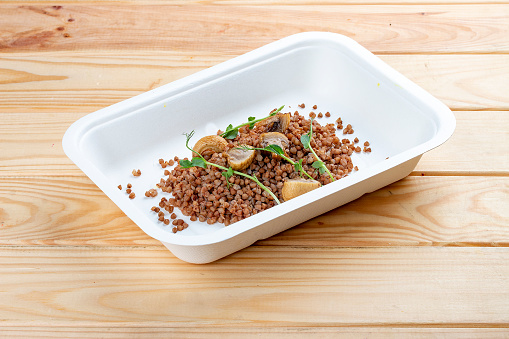 Buckwheat porridge with mushrooms. Healthy food. Takeaway food.  On a wooden background.