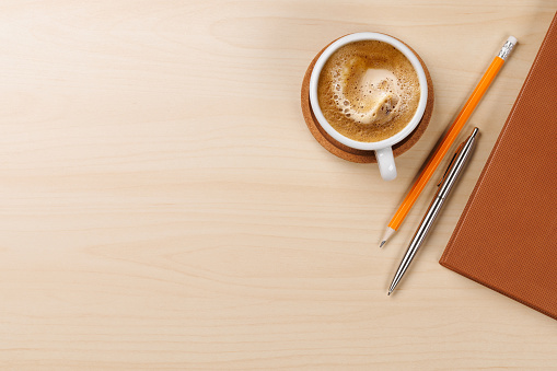 Workplace essentials: Coffee, notepad and supplies. Flat lay with copy space