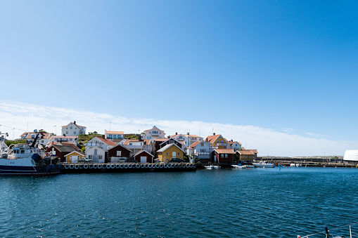 The port of Grundsund, Sweden. Against the backdrop of a picturesque coastal town, the scene captures the rhythmic dance of fishing boats and sailboats, the lively comings and goings of maritime activities, and the enchanting blend of maritime tradition and modern seafaring life. The vibrant colors of the boats, the sounds of water lapping against the docks, and the lively atmosphere of the port showcase the dynamic heart of Grundsund, inviting viewers to immerse themselves in the charm of this coastal gem.
