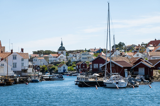 The port of Grundsund, Sweden. Against the backdrop of a picturesque coastal town, the scene captures the rhythmic dance of fishing boats and sailboats, the lively comings and goings of maritime activities, and the enchanting blend of maritime tradition and modern seafaring life. The vibrant colors of the boats, the sounds of water lapping against the docks, and the lively atmosphere of the port showcase the dynamic heart of Grundsund, inviting viewers to immerse themselves in the charm of this coastal gem.