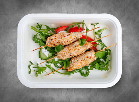 Chicken lula kebab with herbs and vegetables. Healthy food. Takeaway food. Top view, on a gray background.