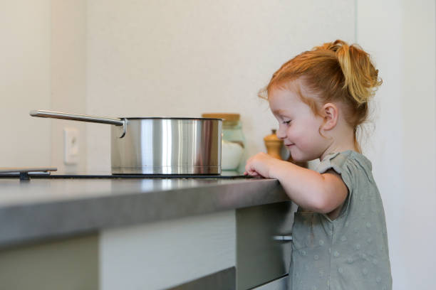Little girl in a kitchen with a metal frying pan stock photo