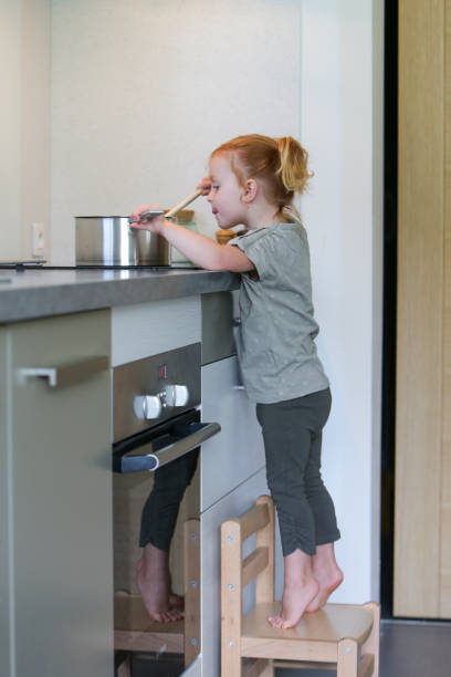istock Little girl in a kitchen with a saucepan 2032321247
