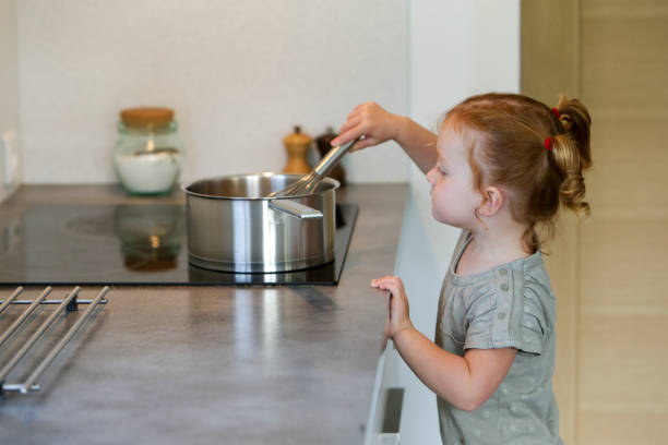 Little girl in a kitchen with a saucepan stock photo