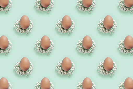 Easter Eggs pattern with White Gypsophila flowers on Light mint green Background. Brown decorated eggs, spring holiday photo, tender soft hues, celebration food and white blooms, Pastel color