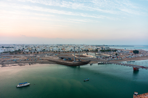 Panoramic view on west part of the Sur city in golden hour. Al Ayjah Bridge, Sur Province, Sur, Oman