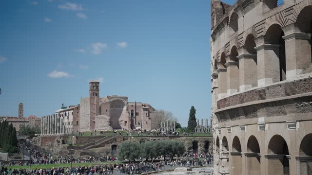 The Colosseum and the Imperial Roman Forum wtih Temple of Venus and Rome in Rome crowded with tourist people, cinematic shot