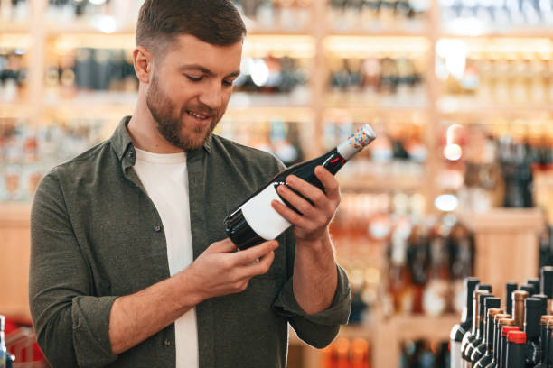 istock Reading information on the bottle. Man is choosing wine in the store 2032375678