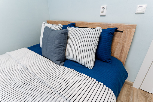 A comforting blue and white striped bed adorned with sheets and pillows, offering a cozy fixture in a building's property or house, crafted with wood and placed on a rectangular floor with exquisite flooring.
