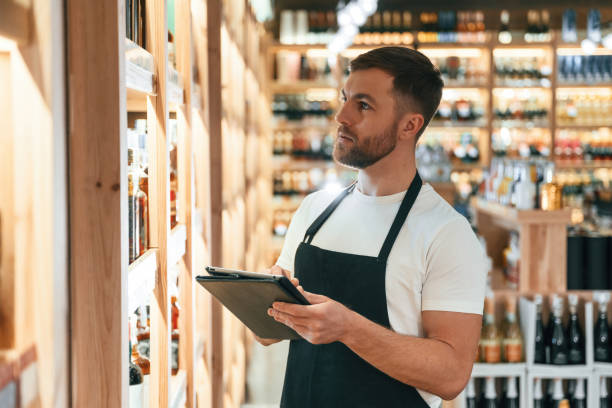 istock Quality control, with notepad. Wine shop owner in white shirt and black apron 2032383321