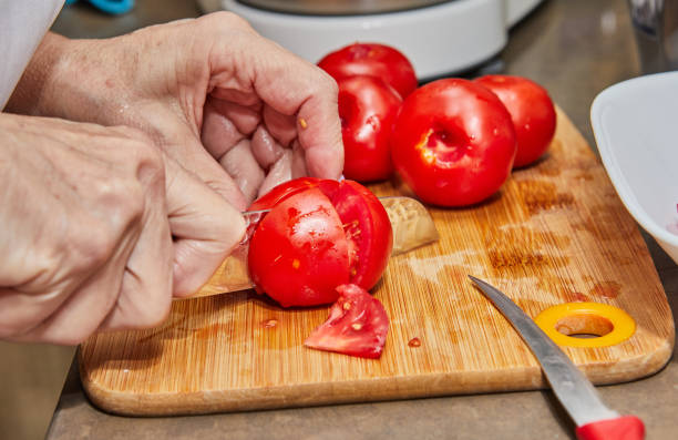 istock Chef's Hands Cutting Fresh Tomatoes on Wooden Cutting Board in Kitchen 2032395001