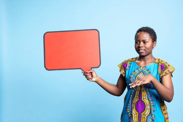 istock African american woman pointing at red speech bubble in studio, 2032419192
