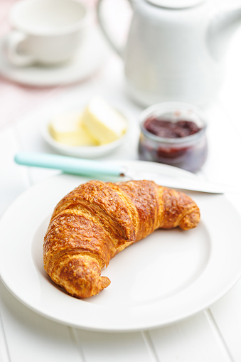 Baked tasty croissant on plate on the white table.