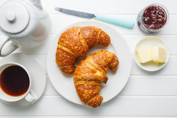 istock Two baked tasty croissants on plate on white table. 2032423002