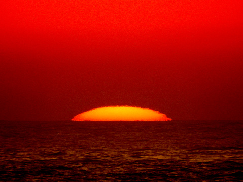 The sun appears over the horizon of the Pacific Ocean.  The colour has been manipulated by changing the \