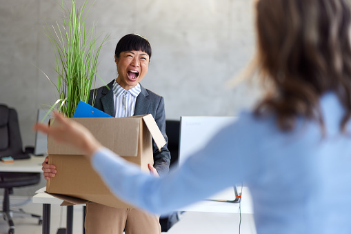 Young Japanese businesswoman feeling ecstatic after quitting from her job in the office.