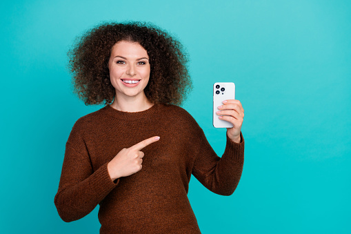Photo portrait of attractive young woman hold point device cheerful wear trendy brown clothes isolated on cyan color background.